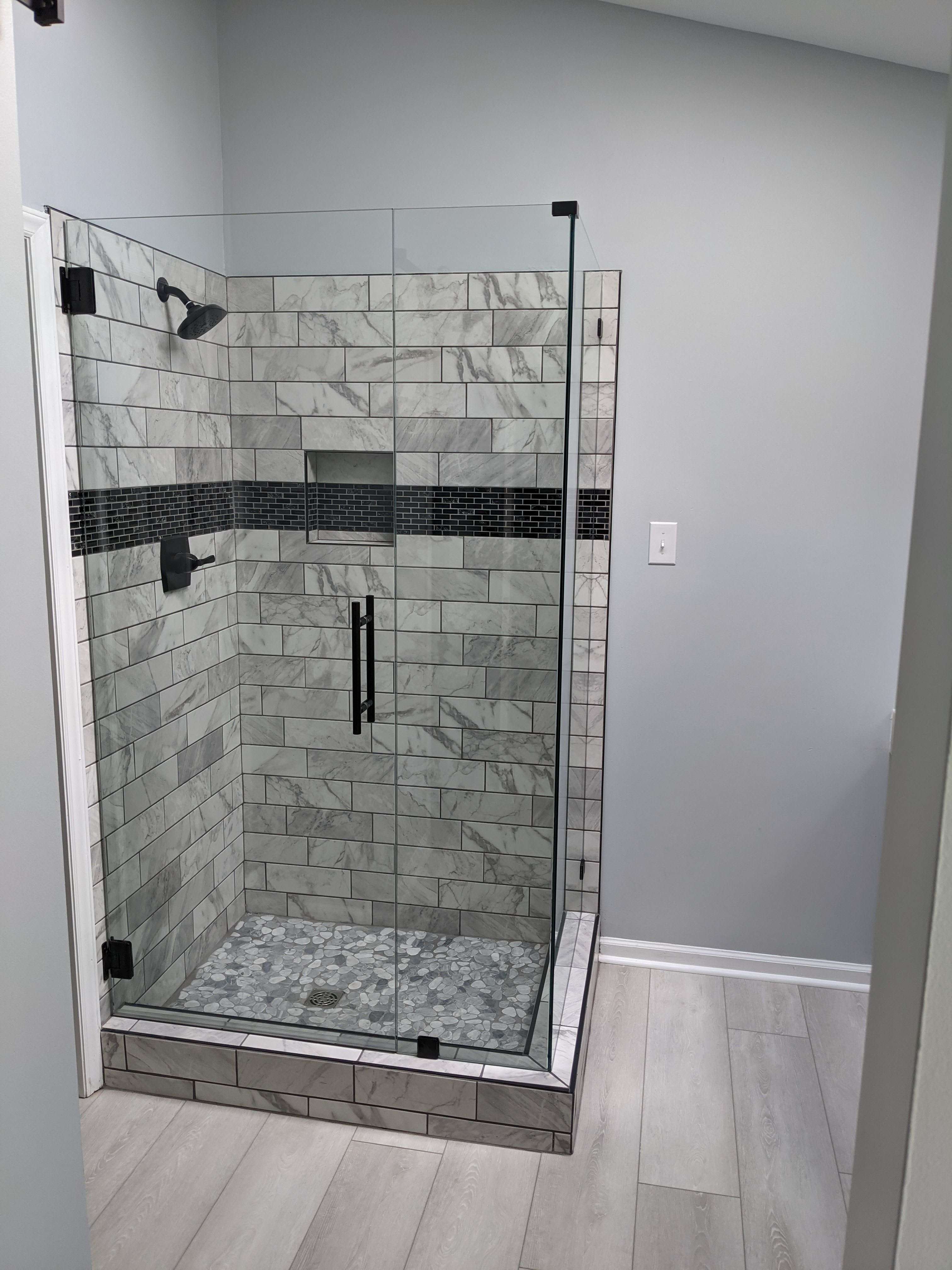 A renovated bathroom with large polished marble-look floor tiles, blue beadboard wainscoting, and a white vanity with gold hardware.