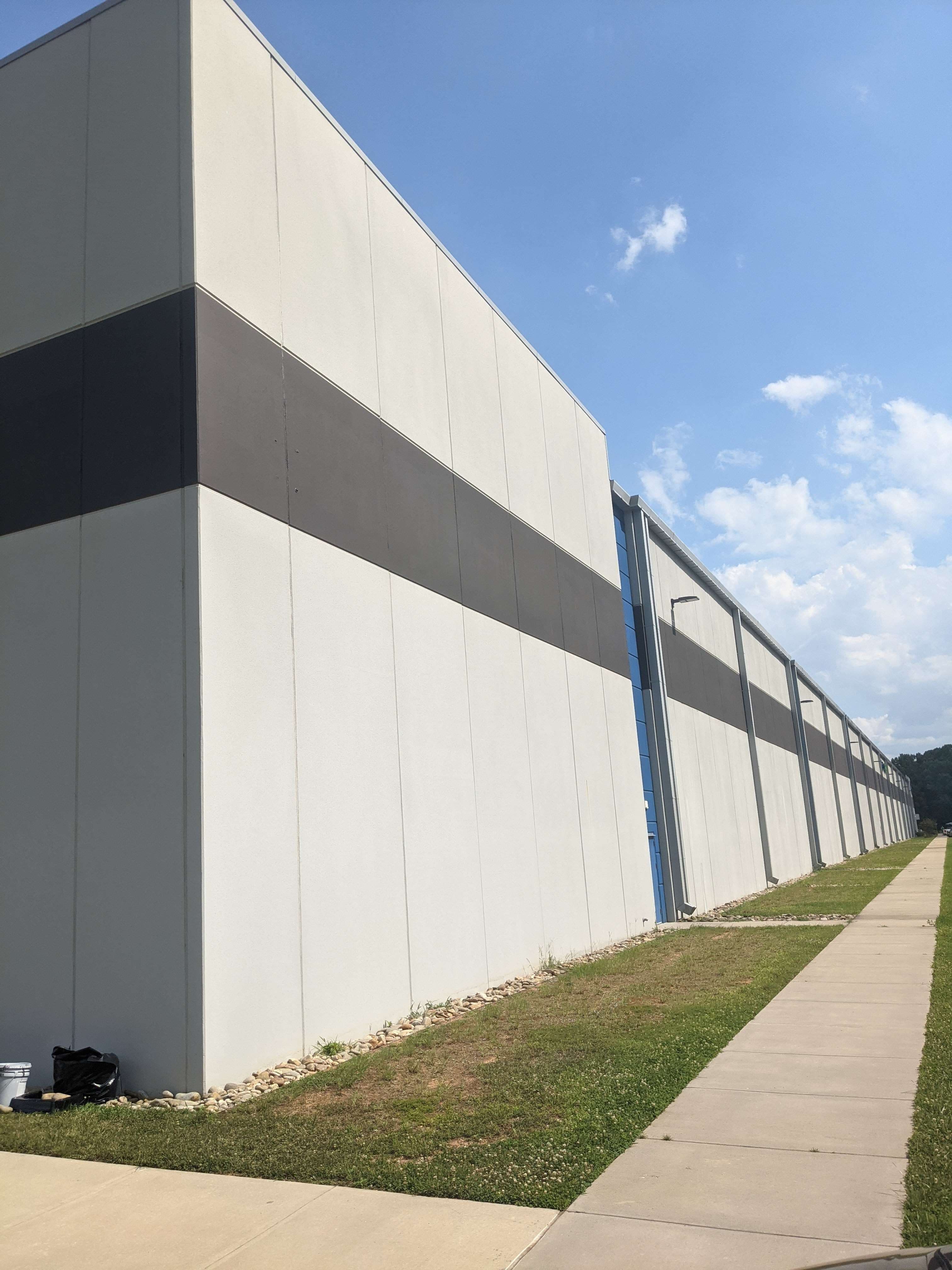 A long commercial building in Davidson with refreshed light grey panels and a high-contrast dark charcoal horizontal stripe.