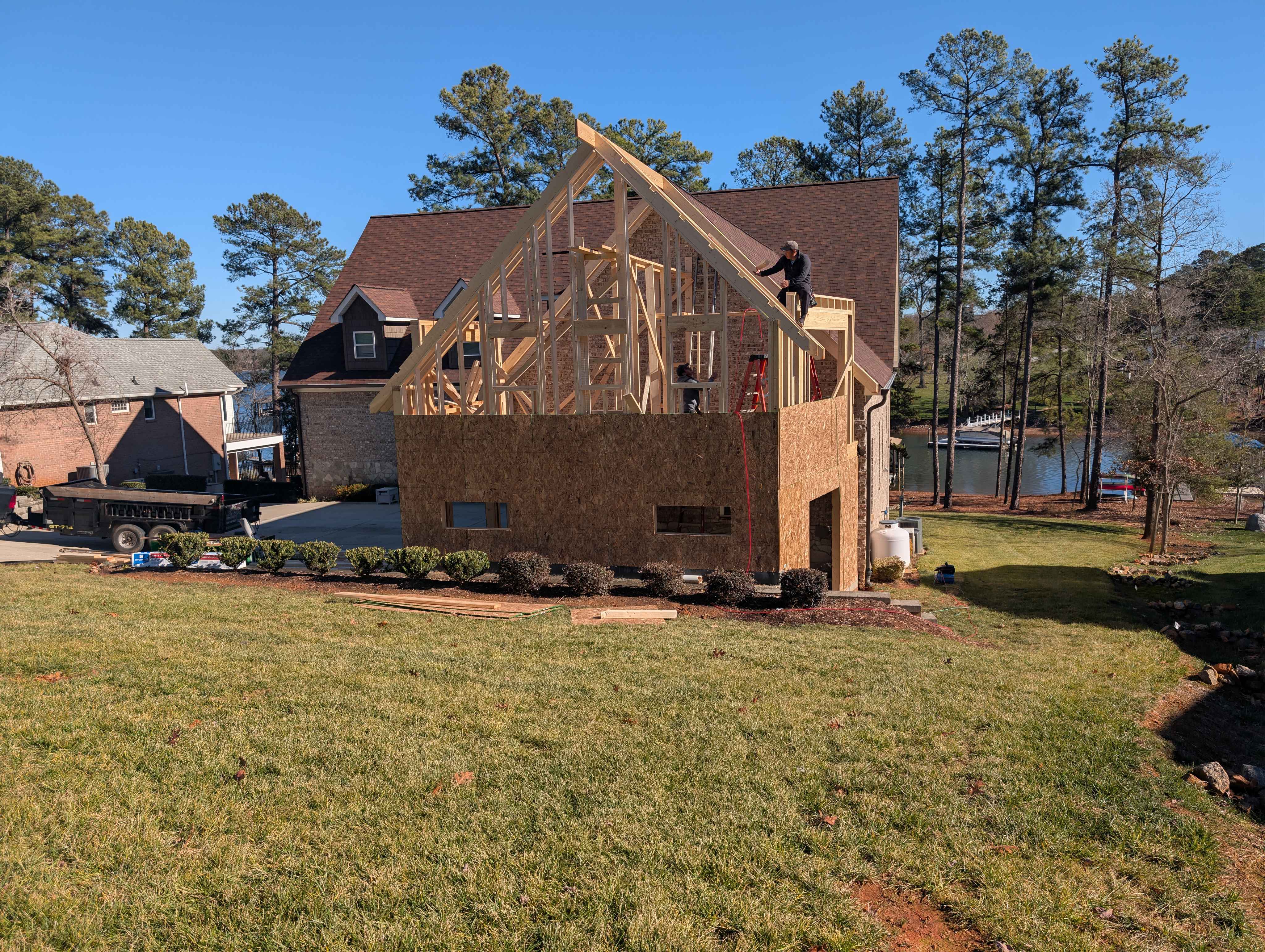 Progressive stages of a residential home addition project, documenting the transition from open wood framing to a dried-in structure with house wrap and roofing.